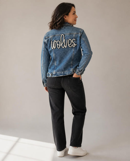 Woman wearing the denim jacket, seen from behind, showing the sequin wolves script patch