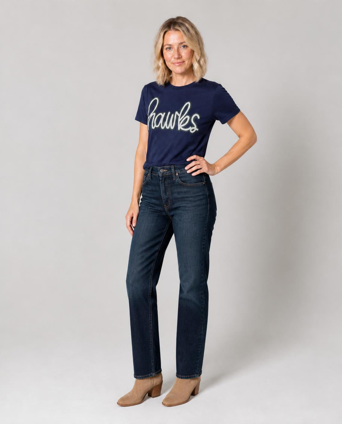 Woman wearing the navy sequin hawks tee with dark jeans and boots